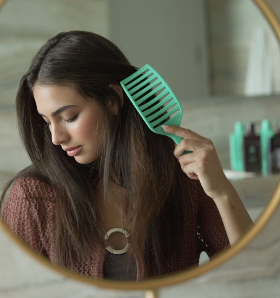 Woman brushing hair with Takkra Aquamarine Brush