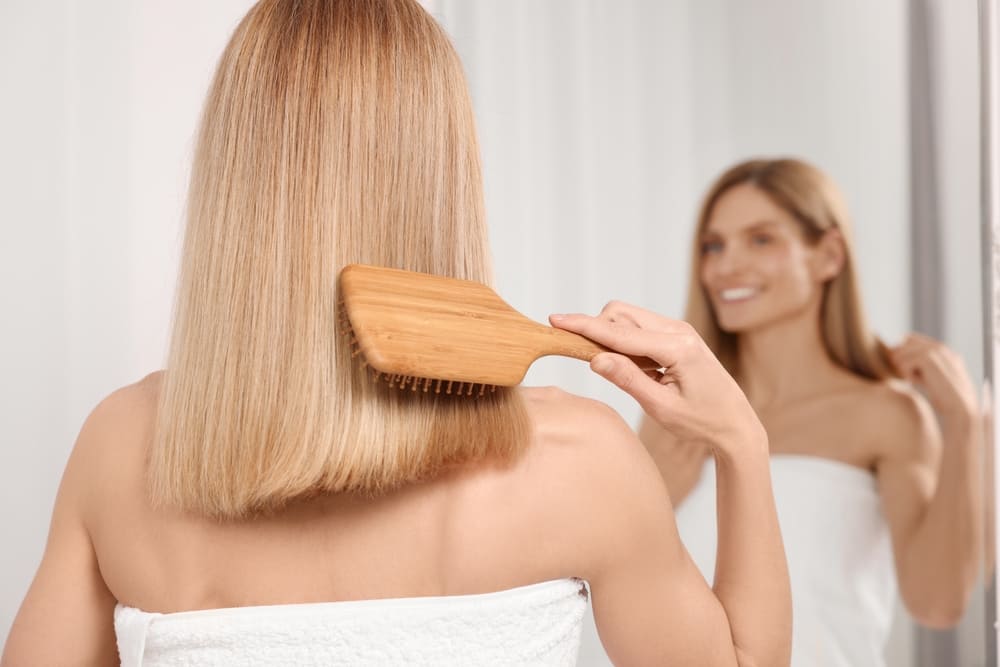 Woman brushing bleached blonde hair
