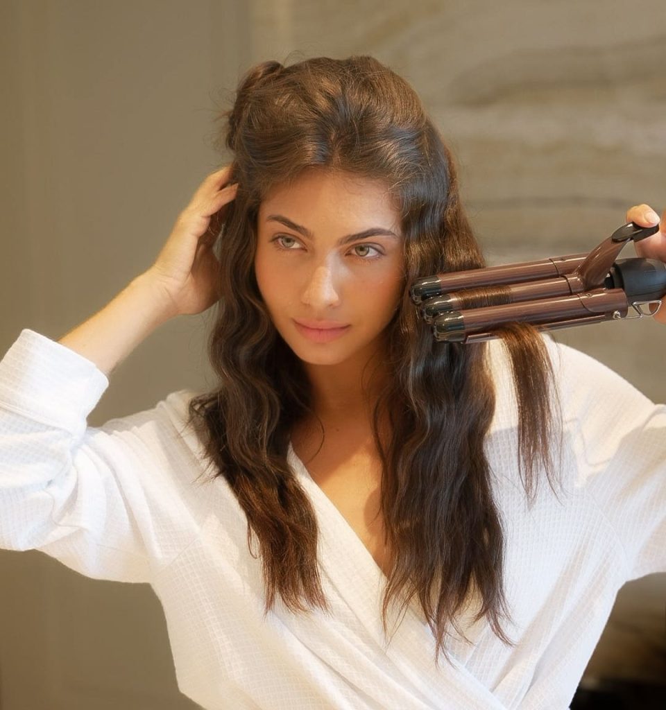 Woman using heated Takkra Glamour Wave Triple Barrel Styler